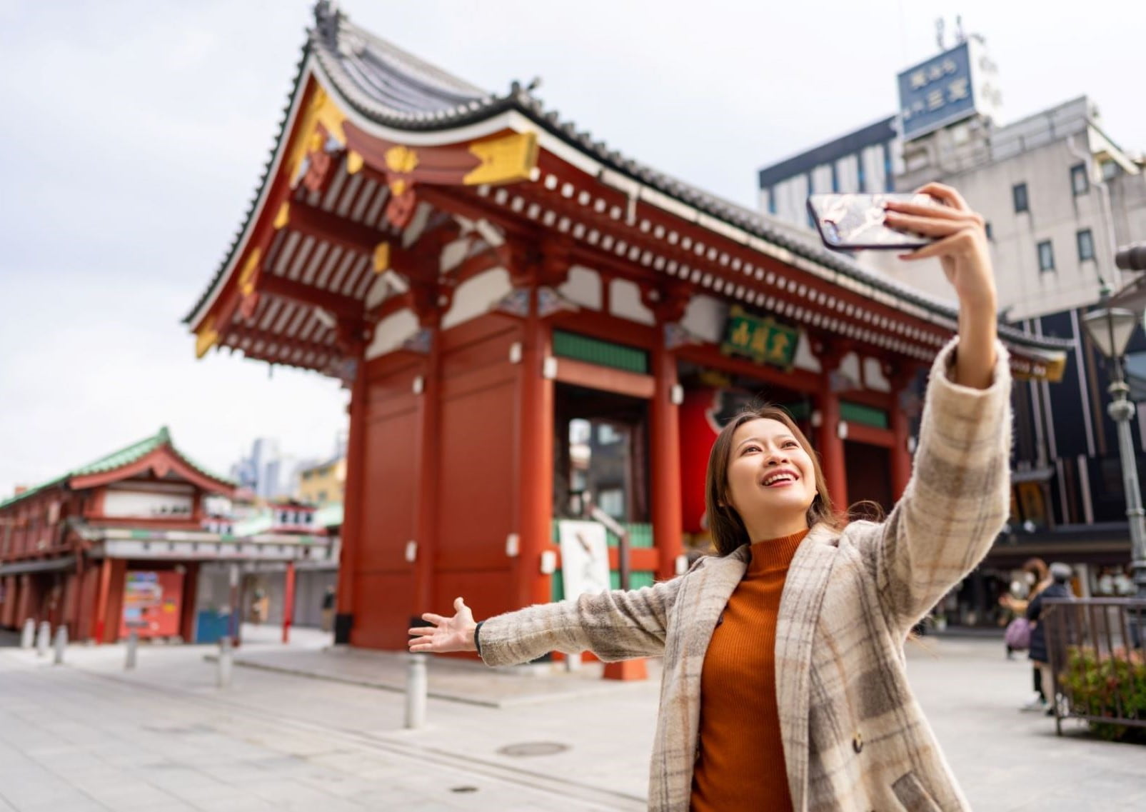 Jente med telefon foran Sensoji Temple, Asakusa, Tokyo, Japan