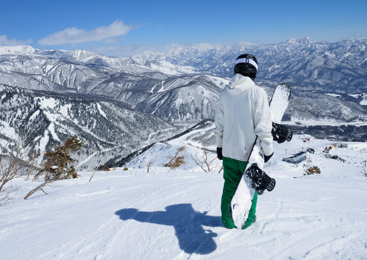 En snowboardkjører ser utover det snødekte landskapet i Hakuba, Japan