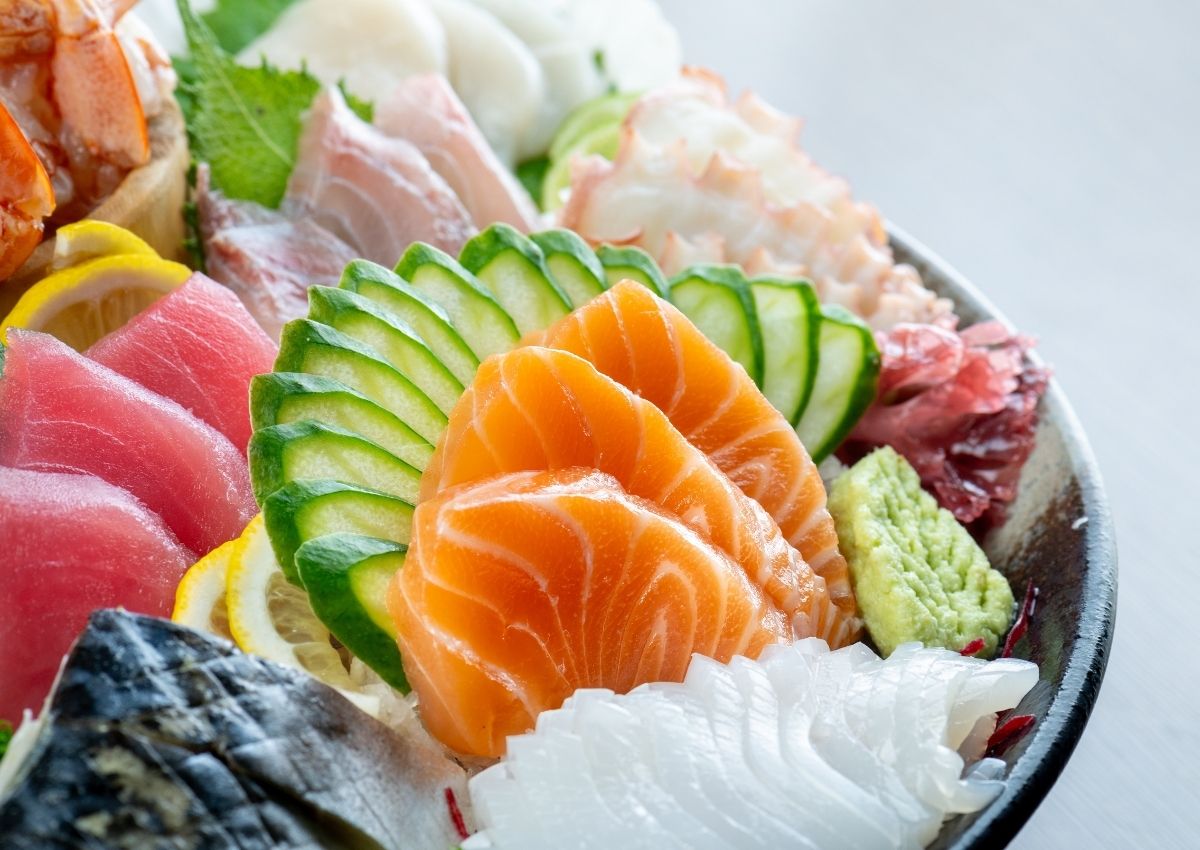 Sashimi av laks og tunfisk, pent dandert i en bolle med sitron, agurk og annen rå fisk.