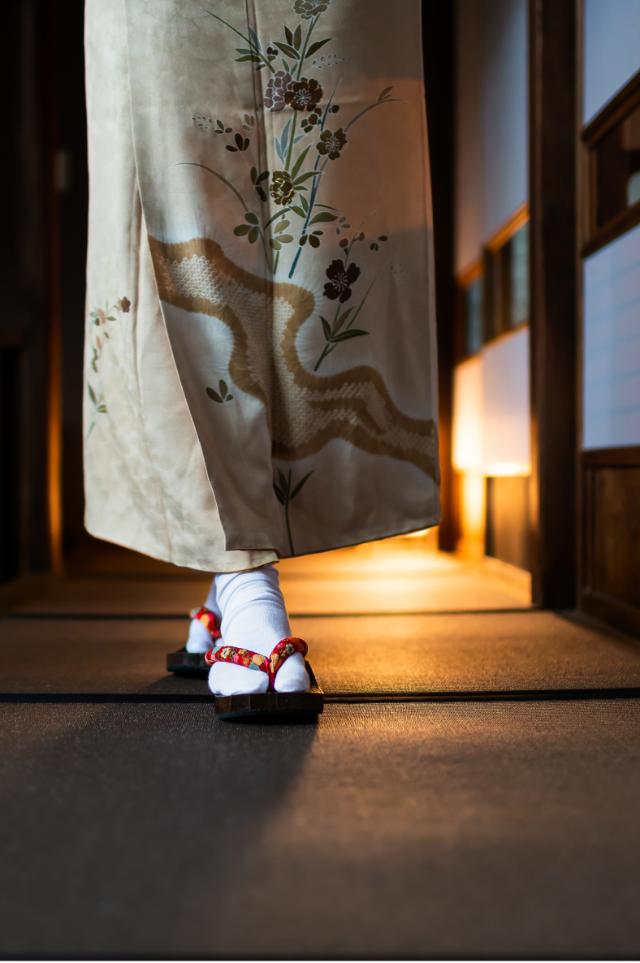 Kvinne i kimono går gjennom en tradisjonell ryokan med tatamimatter og shoji-dører