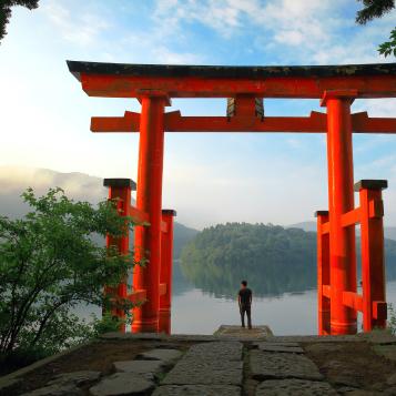 Turist ved den røde torii-porten til Hakone-helligdommen, som ligger ved Ashi-sjøen i Japan