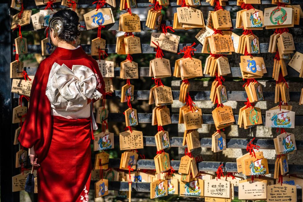 Japansk kvinne leser bønnekort på en treplate ved Kiyomizu-dera-tempelet i Kyoto