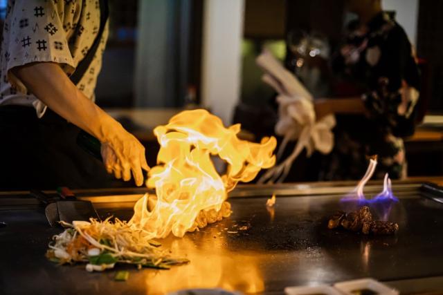 Kokken tilbereder teppanyaki-måltid med innbakt biff og grønnsaker