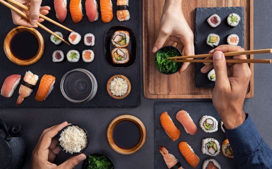 Assortert sushi, inkludert nigiri, sashimi og ruller, som deles og spises med spisepinner