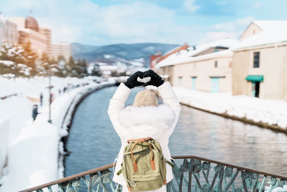 Turister på sightseeing langs den snødekte Otaru-kanalen i Hokkaido, Japan, nyter vintersesongen