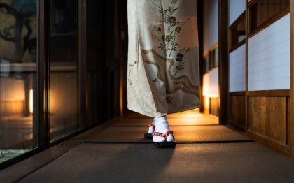 Kvinne i kimono går gjennom en tradisjonell ryokan med tatamimatter og shoji-dører