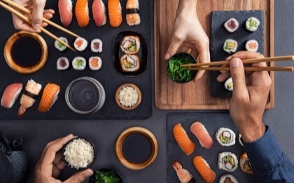 Assortert sushi, inkludert nigiri, sashimi og ruller, som deles og spises med spisepinner