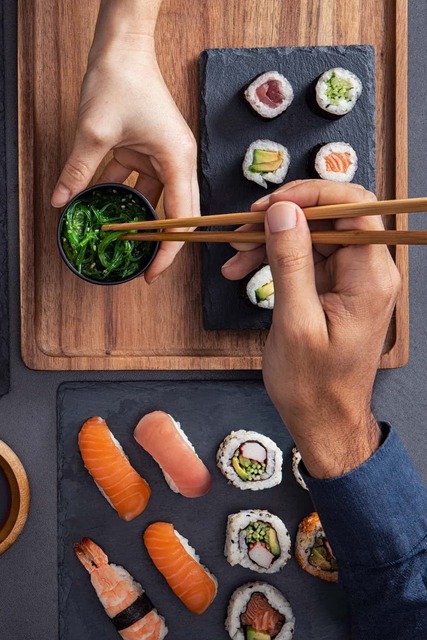Assortert sushi, inkludert nigiri, sashimi og ruller, som deles og spises med spisepinner