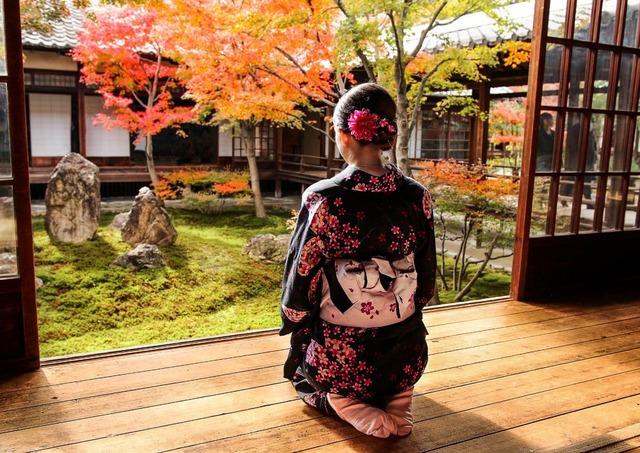 Flicka i kimono under höstens färger i Kyoto, Japan.